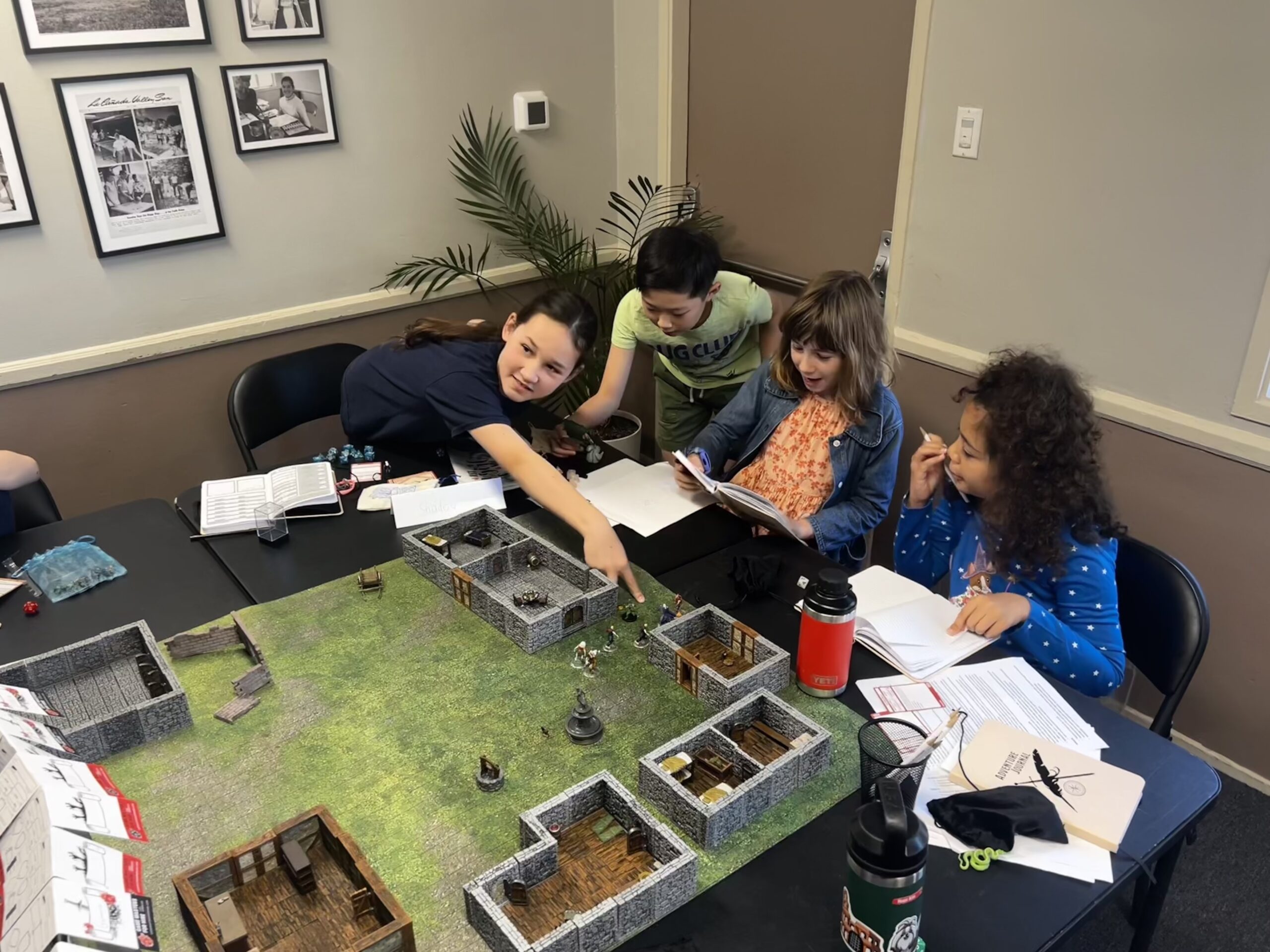 A group of kids point to a the game figures in front of them while playing Dungeons & Dragons.