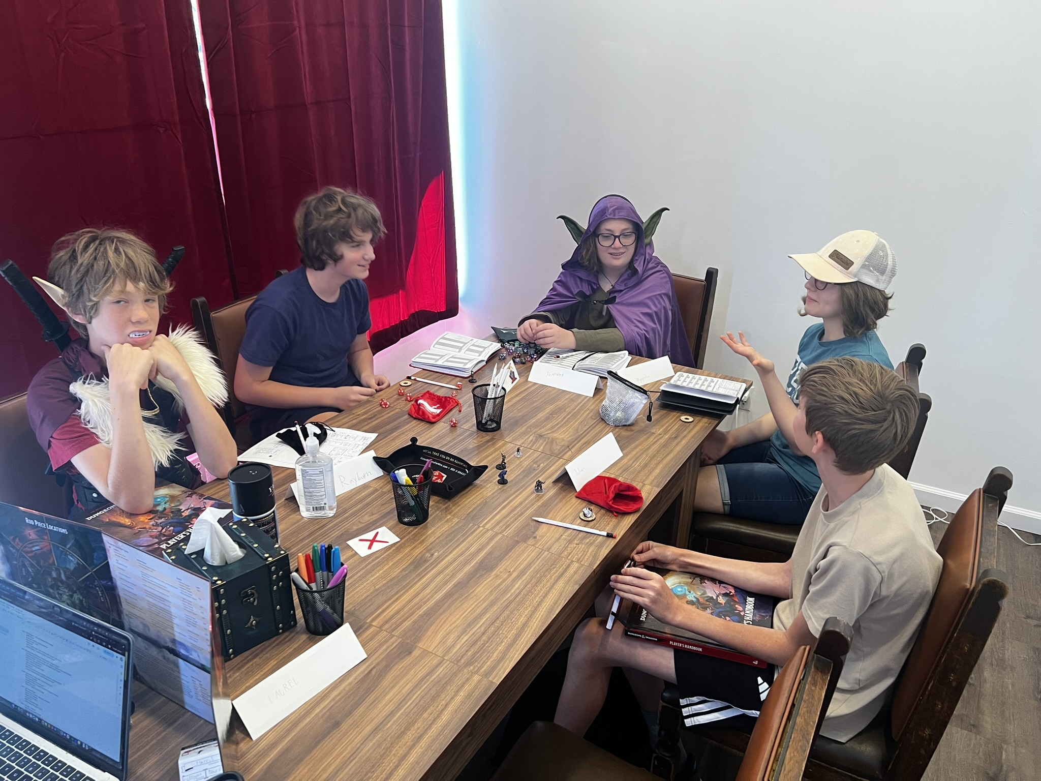 A group of kids point to a the game figures in front of them while playing Dungeons & Dragons.